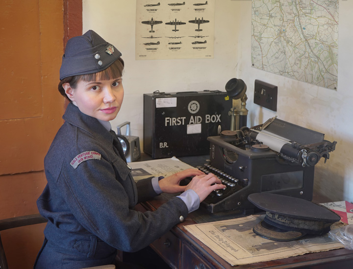 1940s Girl in a Girls Venture Corps Air Wing outfit types on a typewriter